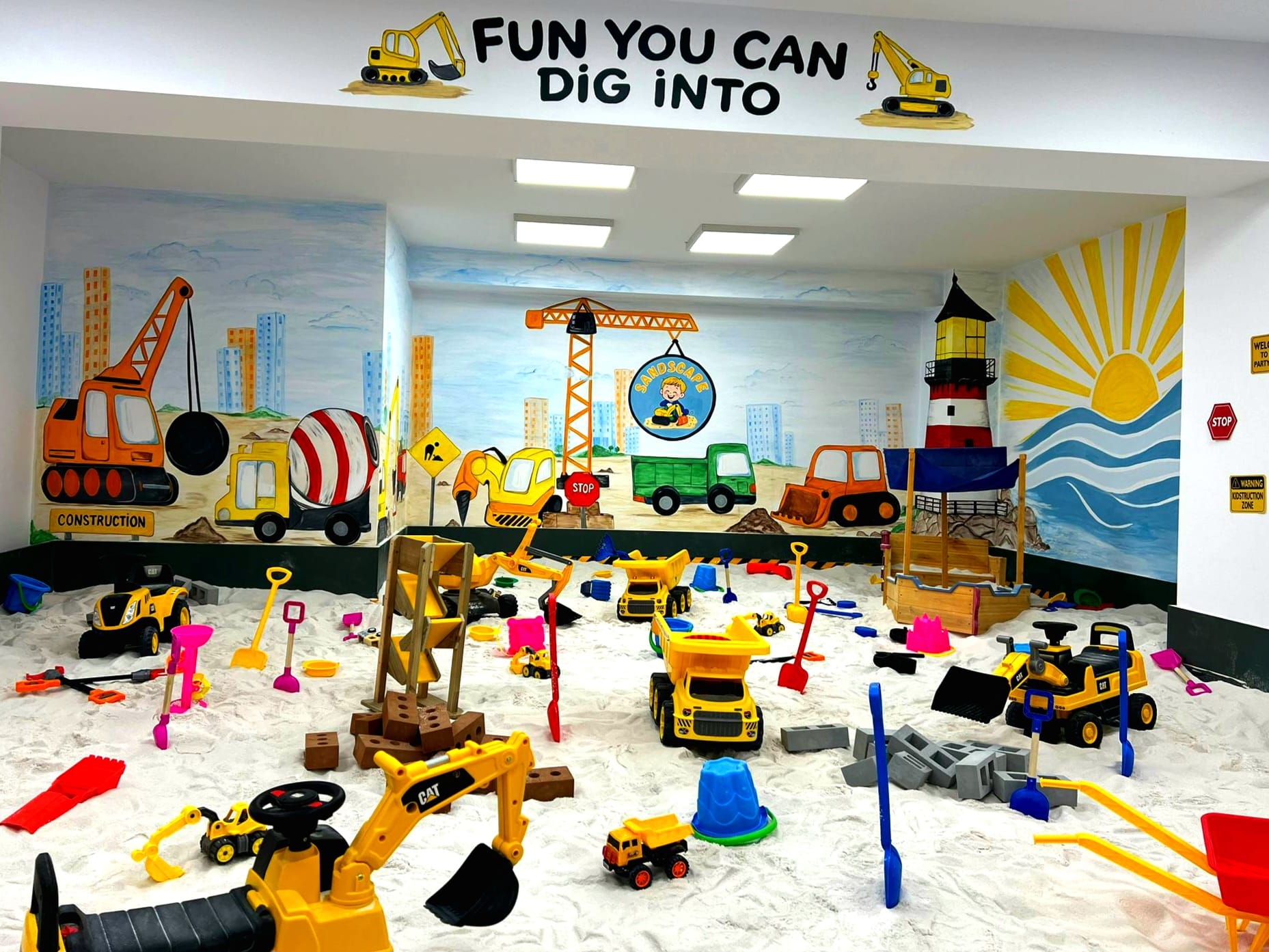 Zonă de joacă interior cu nisip, plină de excavatoare, camioane și jucării la SandScape Iași